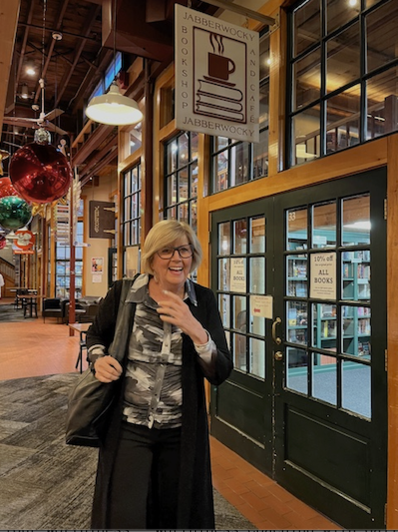 Gail Kauranen Jones smiling beneath the Jabberwocky Bookshop and Café sign at her Born Worthy launch