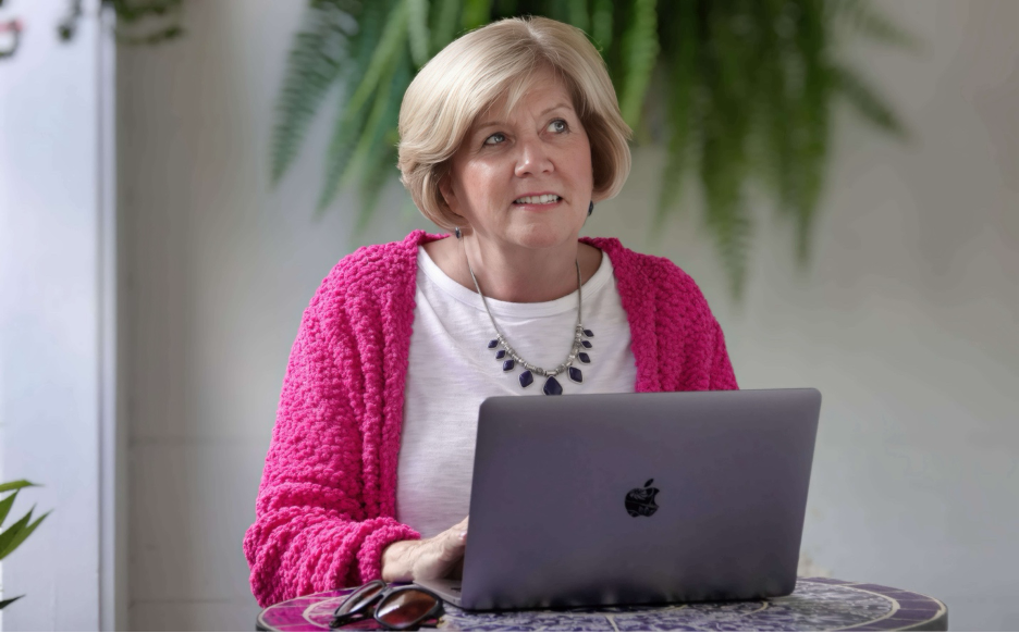 Gail Kauranen Jones seated at her laptop, smiling warmly at the camera